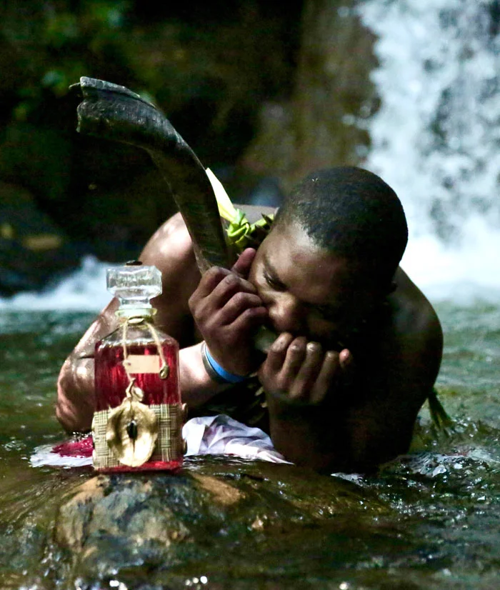 Homme jouant d'un instrument près d'une cascade