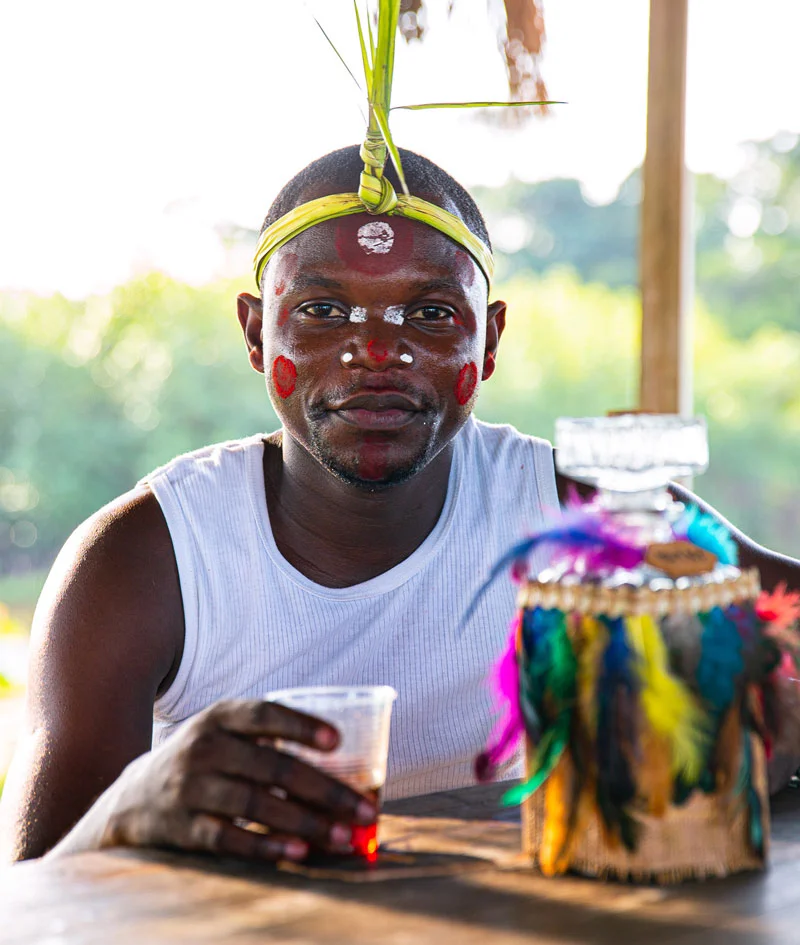 Homme gabonais en tenue traditionnelle, boisson à la main